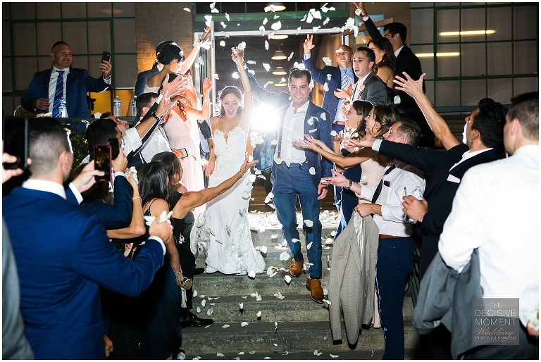 Bride and groom take final departure at end of the night, down stairway as guests throw confetti into the air at Foundry at Puritan Mill wedding